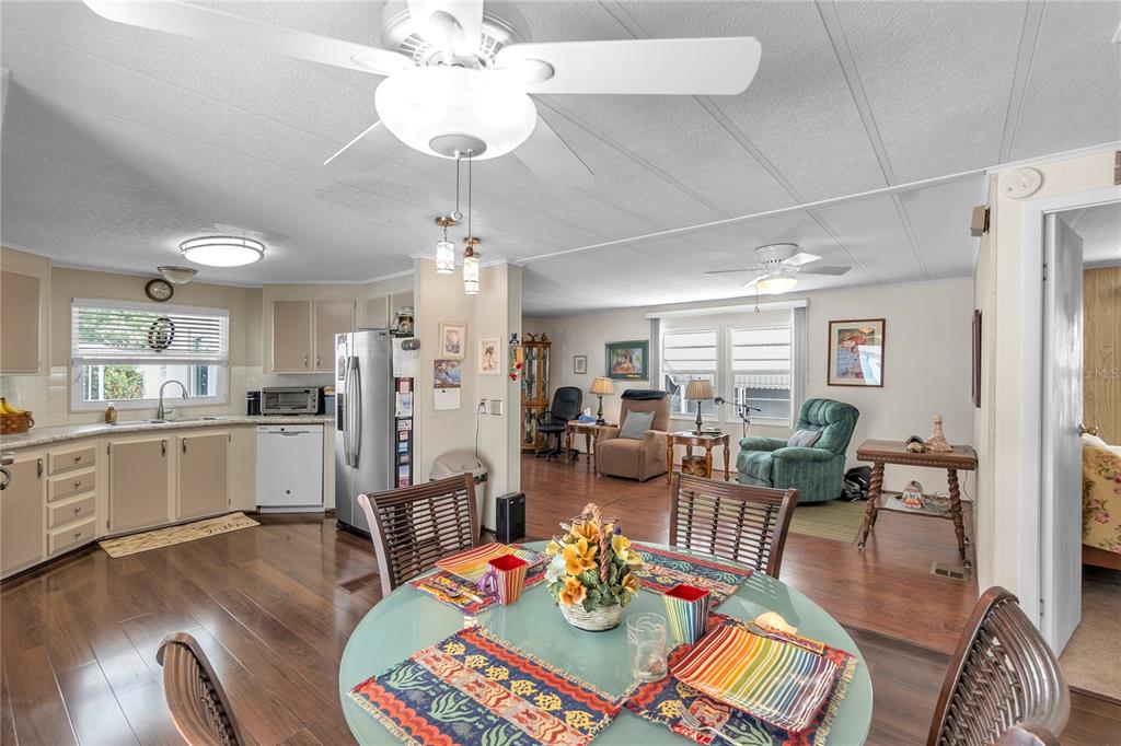 An open-concept kitchen and dining area with wood-look flooring and a ceiling fan — 45 CABALLO WAY, BRADENTON, FL