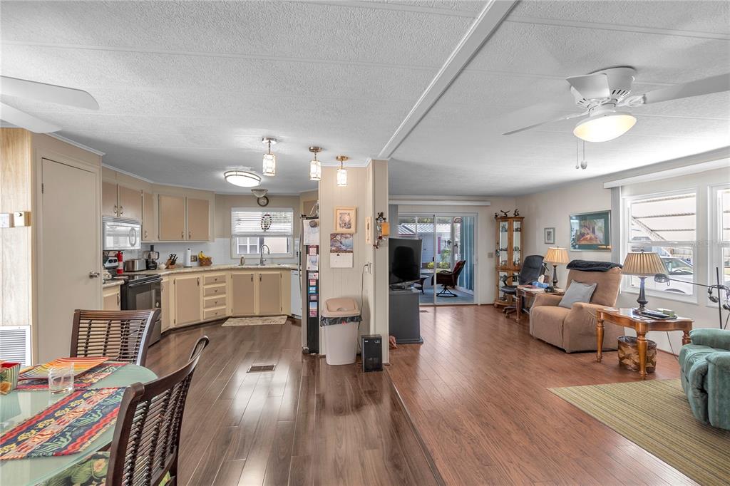 An open-concept living and dining area with wood-look flooring and a kitchen with beige cabinets — 45 CABALLO WAY, BRADENTON, FL