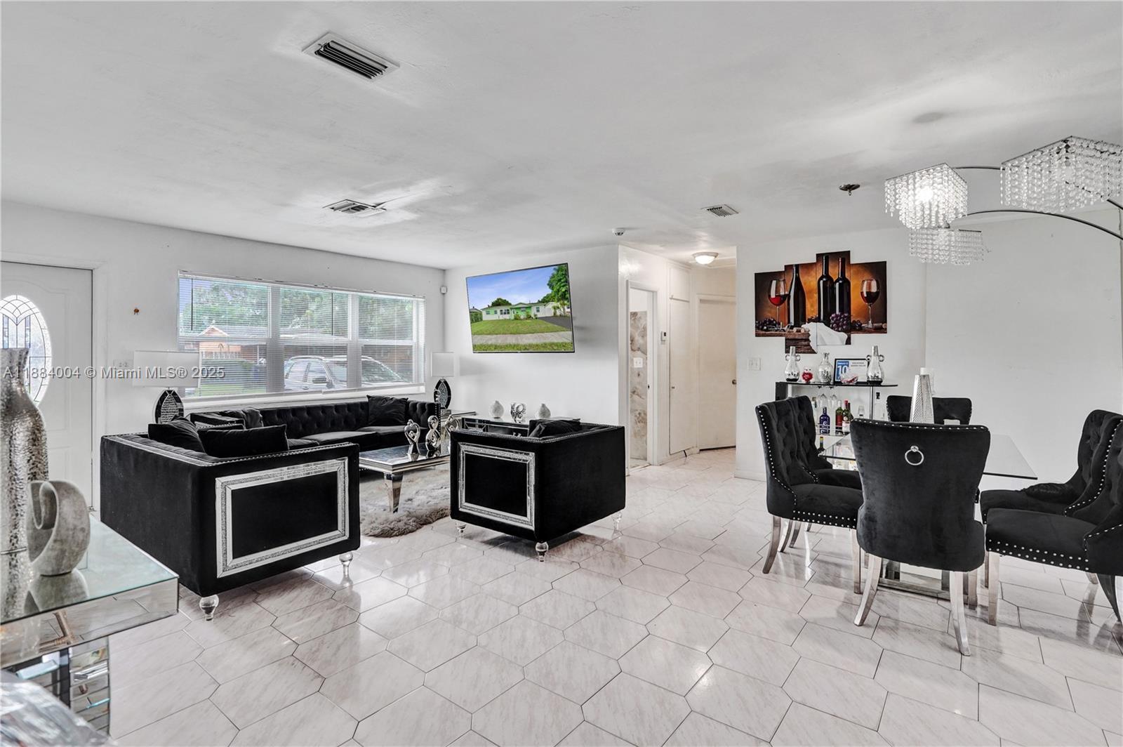 This open-concept living and dining area features white tile flooring and black velvet furniture — 320 N 71st Ave, Hollywood FL 33024, HOLLYWOOD, FL