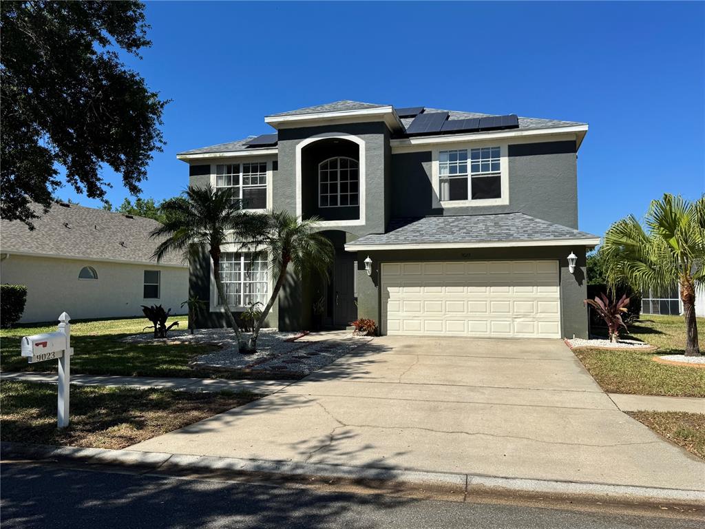 A two-story house with a dark gray exterior, a two-car garage, and solar panels — 9023 PINEBREEZE DRIVE, RIVERVIEW, FL