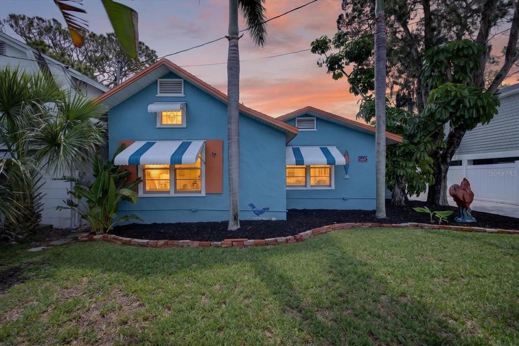 A blue single-story house features striped awnings, orange shutters, and a landscaped front yard — 6202 RIVER ROAD, NEW PORT RICHEY, FL