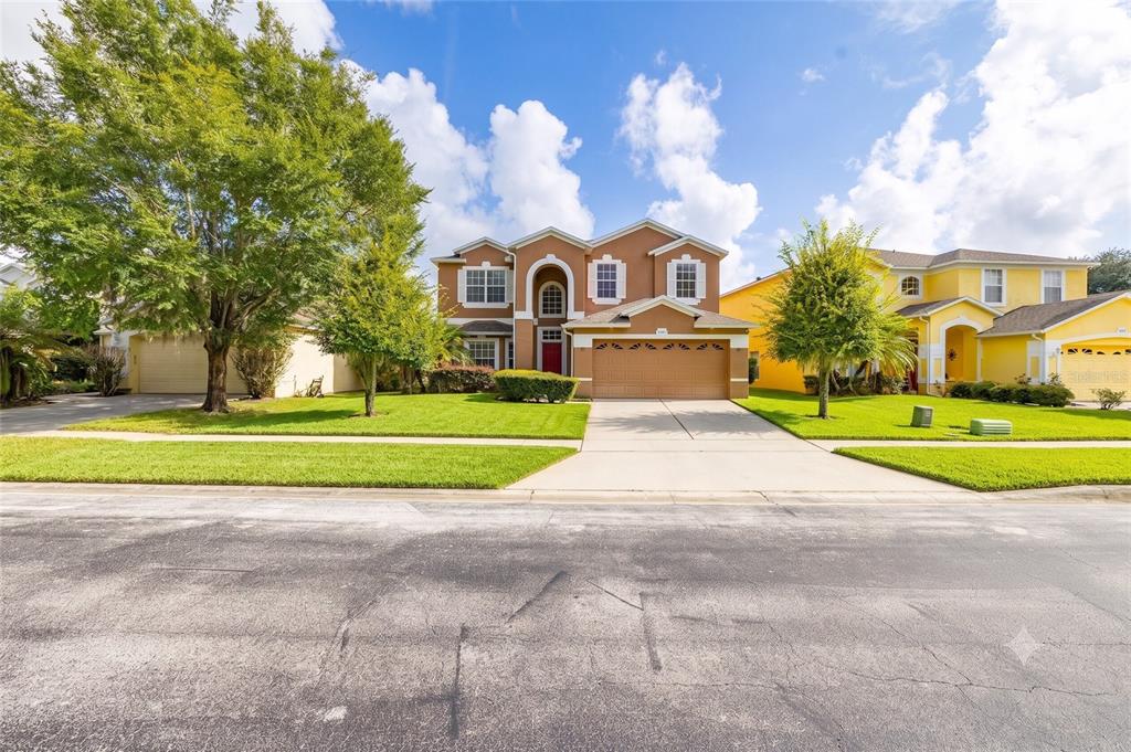 A two-story tan house with a two-car garage and a red front door — 9931 HERON POINTE DRIVE, ORLANDO, FL