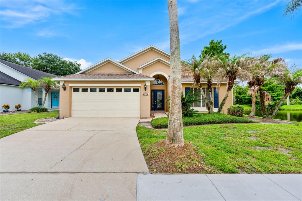 A single-story tan house with a two-car garage and palm trees in the front yard — 114 STONE GABLE CIRCLE, WINTER SPRINGS, FL