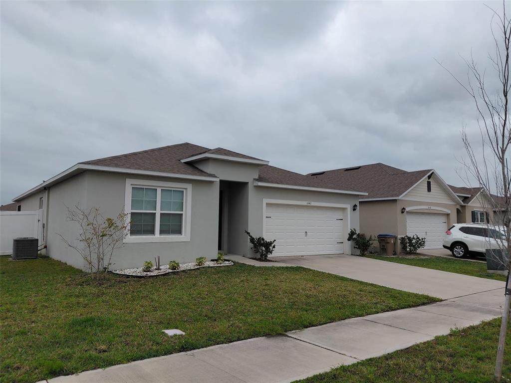 A single-story suburban house with a light gray stucco exterior and a two-car garage — 1842 EGRET MEADOWS AVENUE, KISSIMMEE, FL