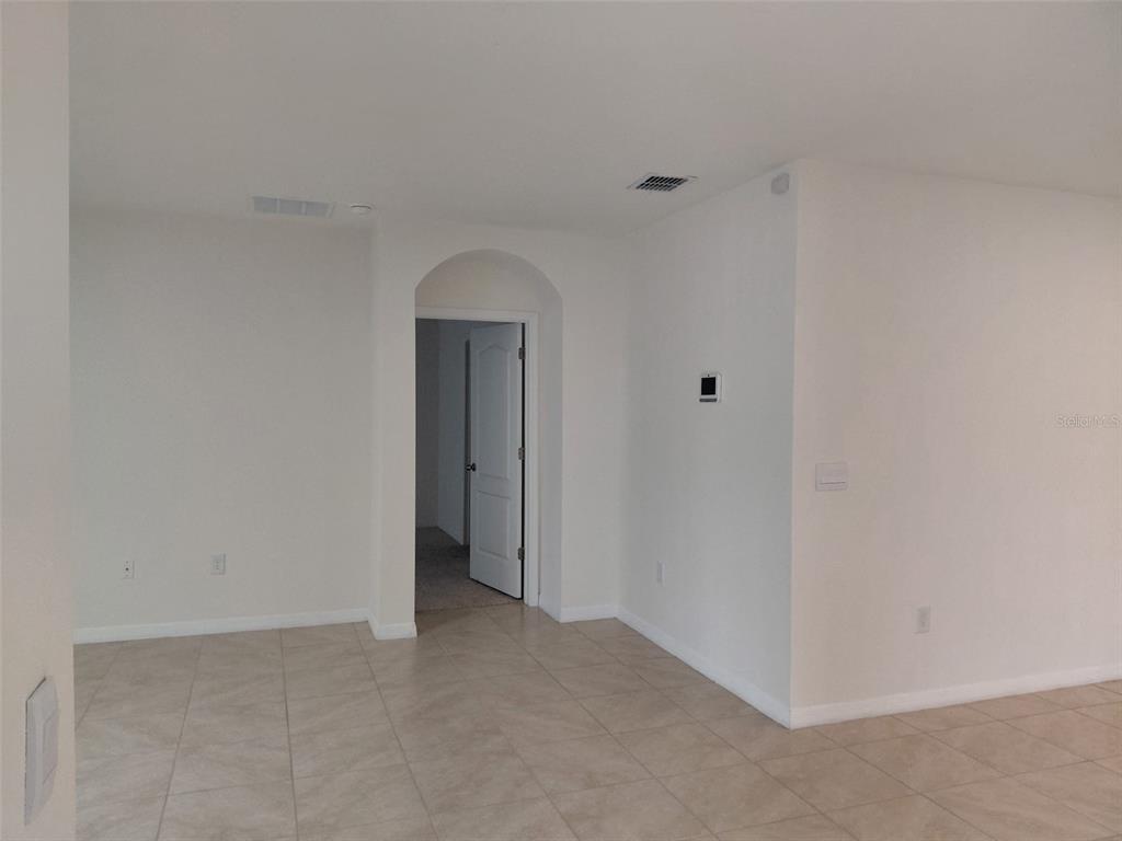 A room with beige tile flooring, white walls, and an arched doorway leading to another room — 1842 EGRET MEADOWS AVENUE, KISSIMMEE, FL