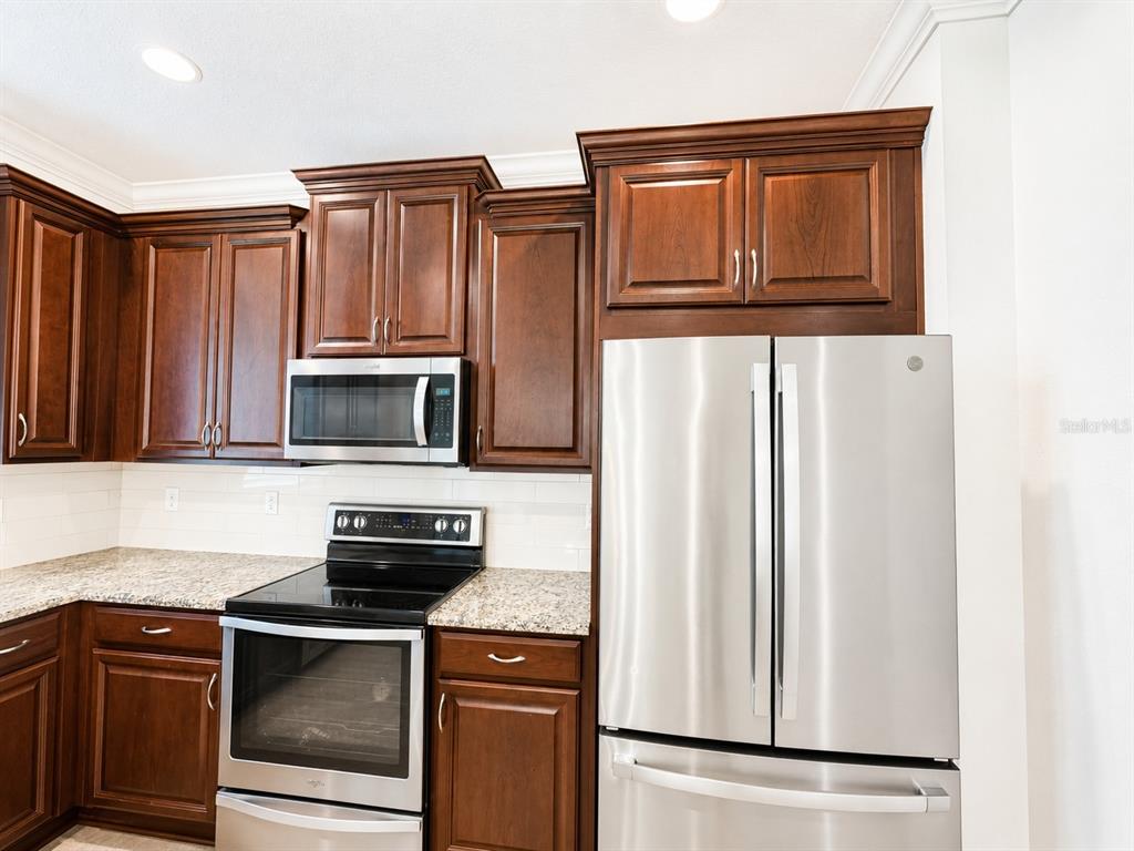 A kitchen features dark wood cabinets, stainless steel appliances, and granite countertops — 12365 TRAILHEAD DRIVE, LAKEWOOD RANCH, FL