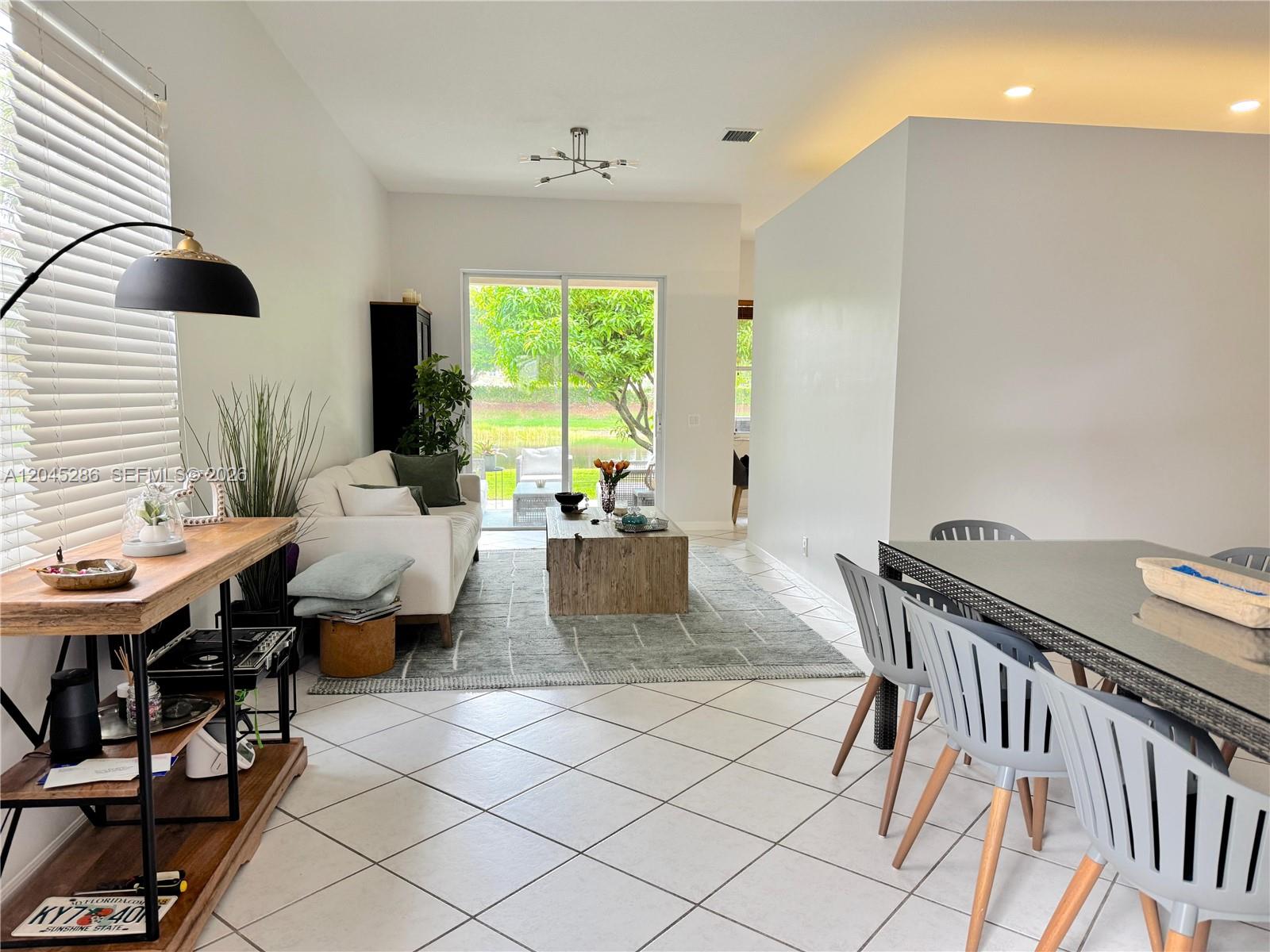 A living and dining area features white tile floors, a wooden coffee table, and sliding doors — 1074 Bluewood Ter # 0, Weston FL 33327, WESTON, FL