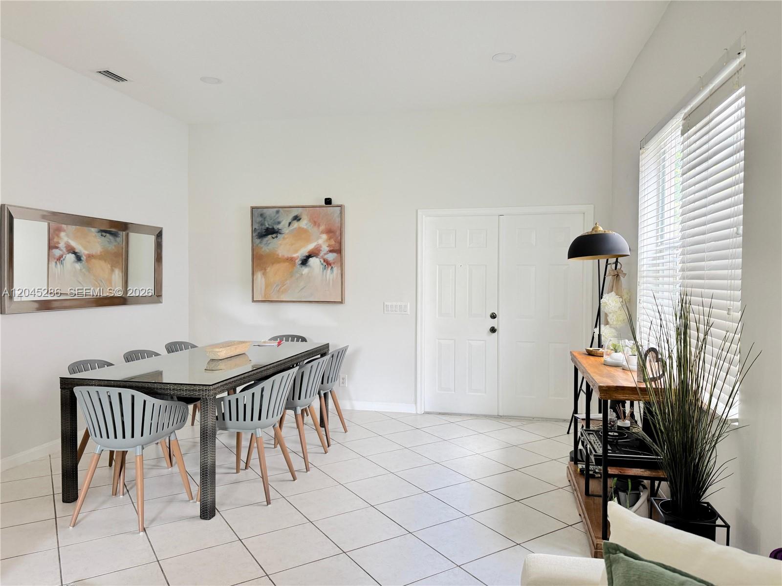 A dining room features a glass-topped table, gray chairs, tile flooring, and a console table — 1074 Bluewood Ter # 0, Weston FL 33327, WESTON, FL