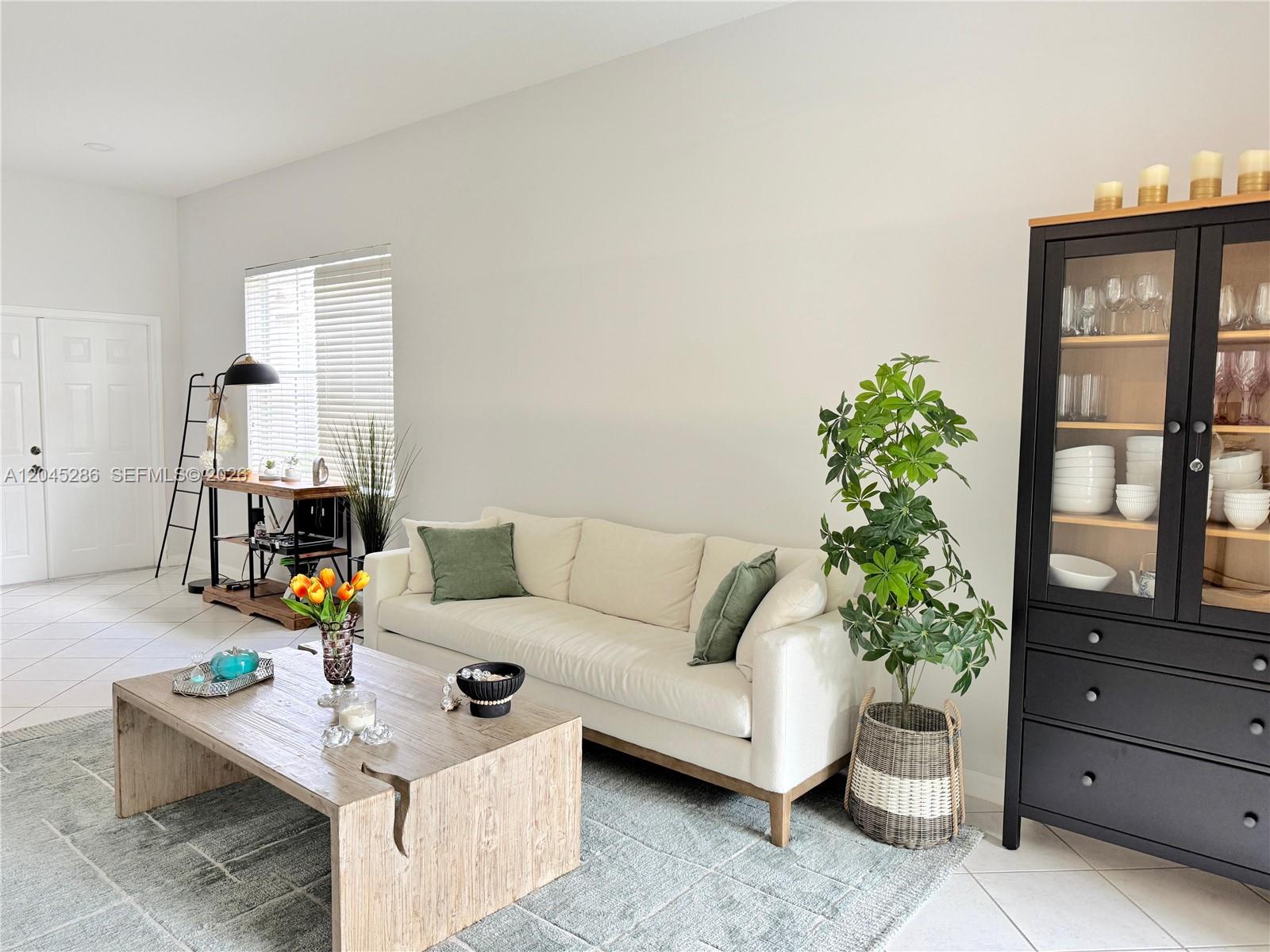 A living room features a white sofa, a wooden coffee table, and a black cabinet — 1074 Bluewood Ter # 0, Weston FL 33327, WESTON, FL