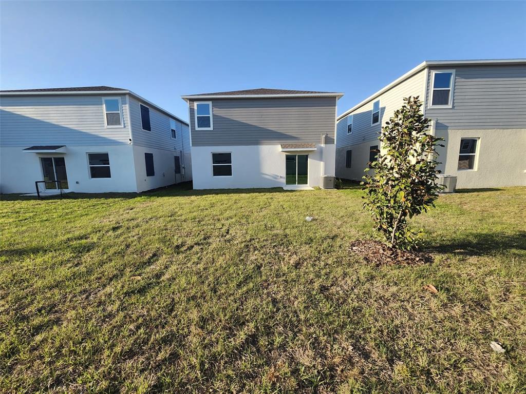 The rear exterior view shows three two-story houses with white stucco and gray siding — 3898 AMERS LOOP, HAINES CITY, FL