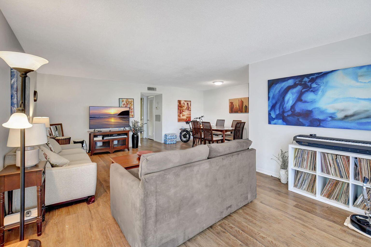A living and dining area with light wood floors, two sofas, and a white bookshelf — 170 High Point Terrace E Apt B, Delray Beach FL 33445, DELRAY BEACH, FL