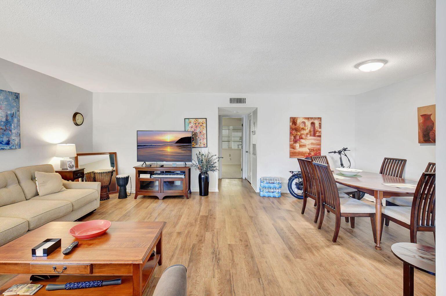 A living and dining room with wood-look flooring, a beige sofa, and a wooden table — 170 High Point Terrace E Apt B, Delray Beach FL 33445, DELRAY BEACH, FL