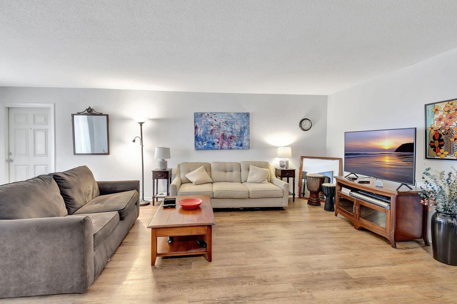 A living room features a grey sofa, a beige sofa, a coffee table, and a television — 170 High Point Terrace E Apt B, Delray Beach FL 33445, DELRAY BEACH, FL