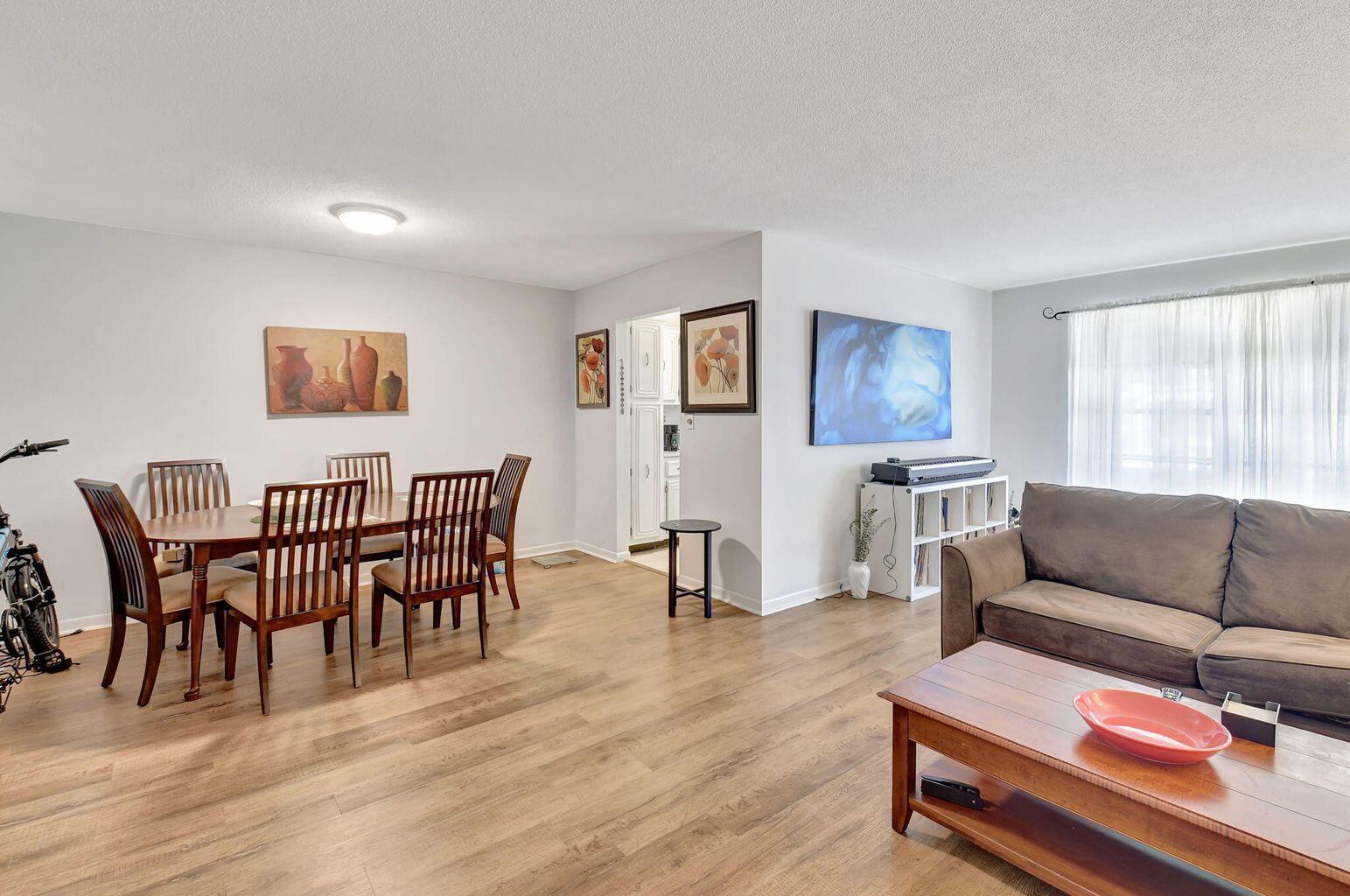 A dining area and living room with wood-look flooring, a brown sofa, and wooden furniture — 170 High Point Terrace E Apt B, Delray Beach FL 33445, DELRAY BEACH, FL