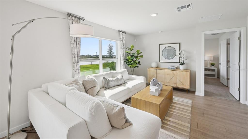 A bright living room features a white sectional sofa, wood coffee table, and large windows — 1524 POWELL VALLEY DRIVE, PORT CHARLOTTE, FL