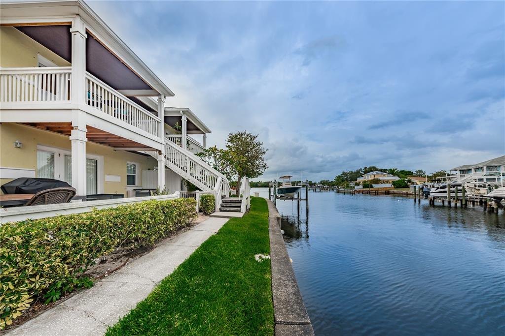 A two-story house with a balcony sits beside a canal with a boat lift — 5004 STARFISH DRIVE SE UNIT F, ST PETERSBURG, FL