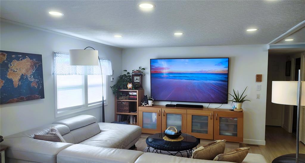A living room features a large television, a light-colored sectional sofa, and recessed lighting — 714 48TH B AVENUE E, BRADENTON, FL