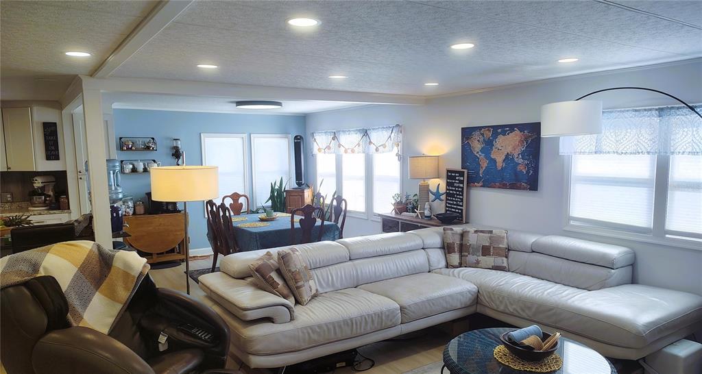 An open-concept living and dining area features a large sectional sofa and light-colored walls — 714 48TH B AVENUE E, BRADENTON, FL