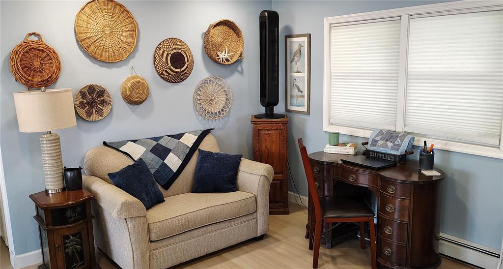 A room features a loveseat, a desk, a lamp, and decorative woven baskets on the wall — 714 48TH B AVENUE E, BRADENTON, FL