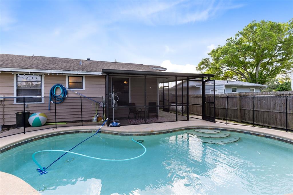 A backyard features a swimming pool with a screened-in patio and a wooden fence — 118 GEORGIA AVENUE, ST CLOUD, FL