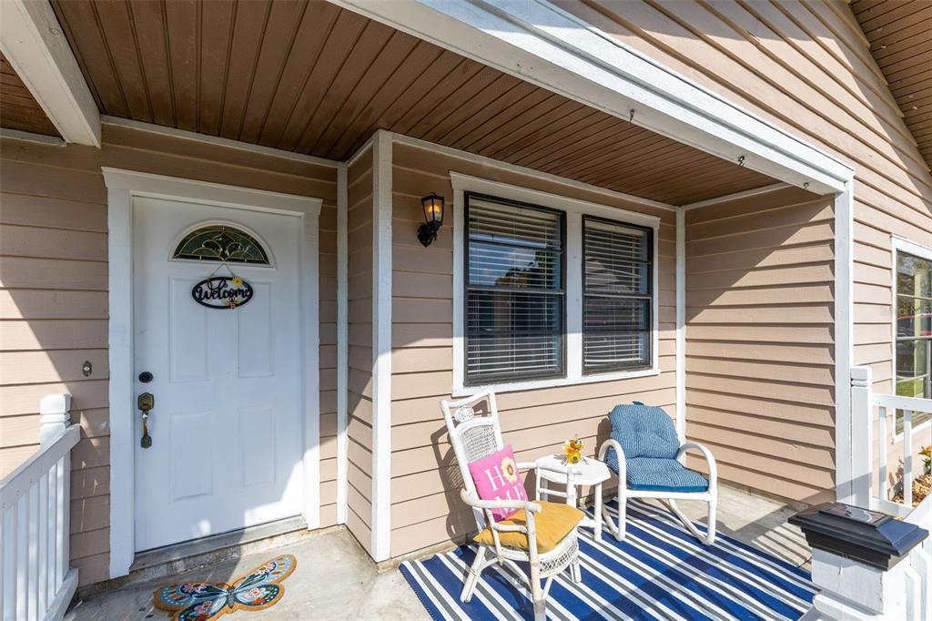 A front porch features a white door, two chairs, a small table, and striped flooring — 118 GEORGIA AVENUE, ST CLOUD, FL