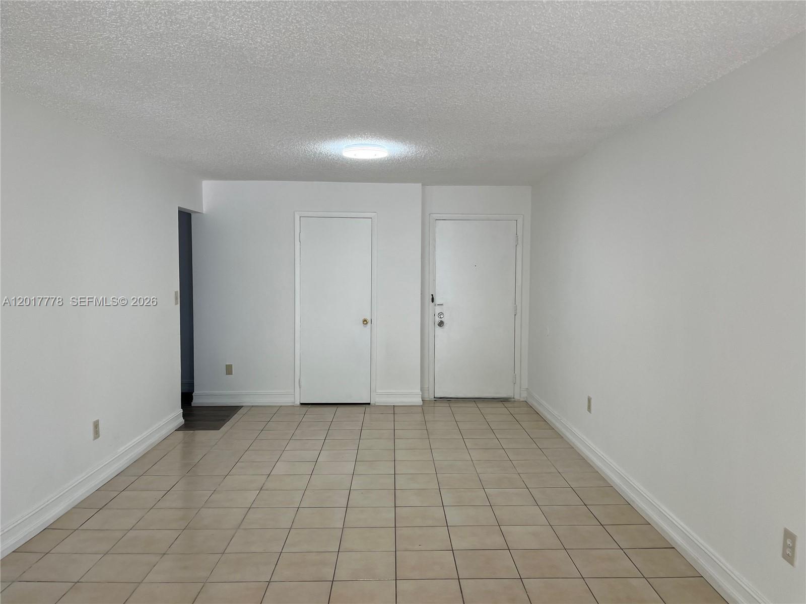 An empty room features white walls, a tiled floor, and two white doors — 9190 Fontainebleau Blvd # 202, Miami FL 33172, MIAMI, FL