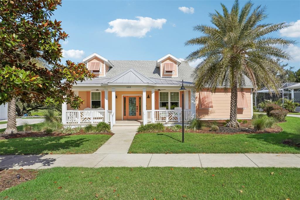 A peach-colored house with a front porch, dormer windows, and a large palm tree — 1212 FIESTA KEY CIRCLE, LADY LAKE, FL