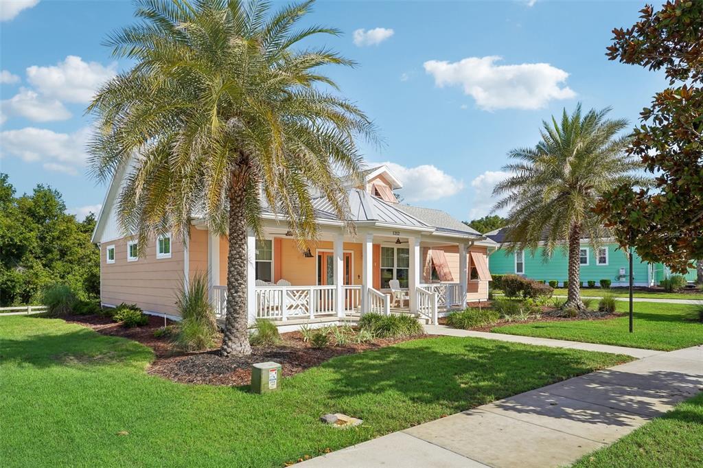 A peach-colored house with a metal roof and a front porch sits on a lawn — 1212 FIESTA KEY CIRCLE, LADY LAKE, FL