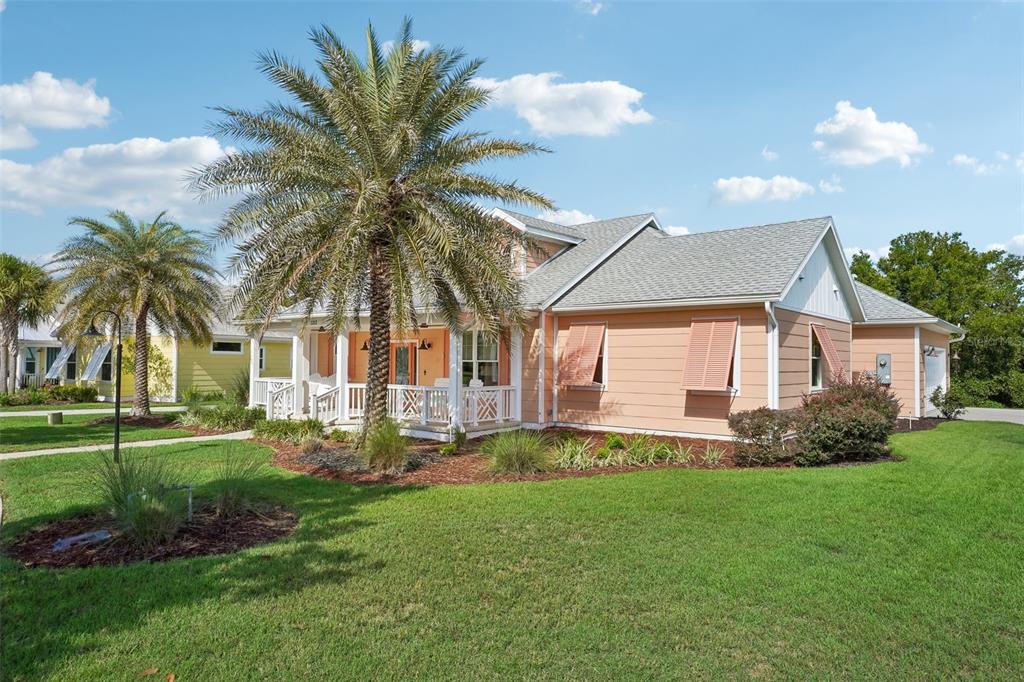 A peach-colored house with a front porch, palm trees, and a green lawn — 1212 FIESTA KEY CIRCLE, LADY LAKE, FL
