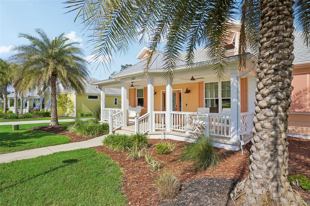 A peach-colored house with a white front porch and palm trees in the yard — 1212 FIESTA KEY CIRCLE, LADY LAKE, FL