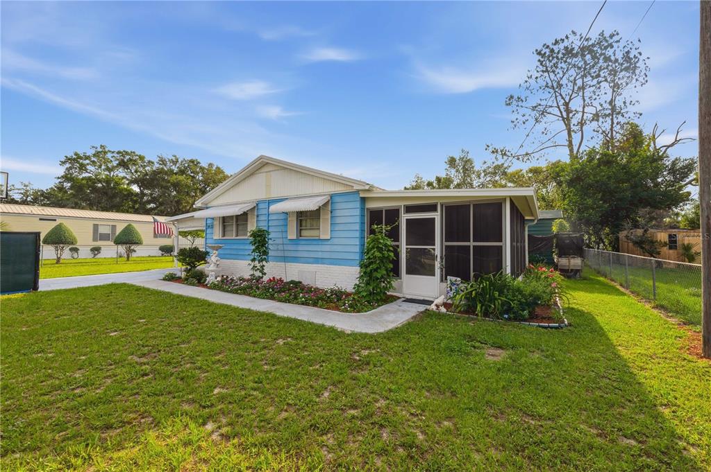 A blue single-story house with a screened-in porch and a front garden on a lawn — 14121 SE 91ST COURT, SUMMERFIELD, FL
