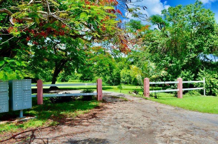 A gravel driveway leads past a white fence and a cluster of mailboxes toward trees — 74 Et Al Lane, VI 00840, VI