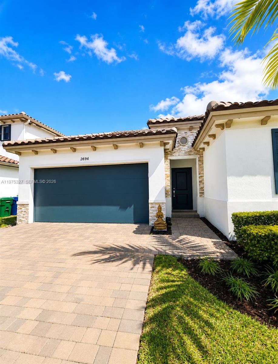 A single-story house exterior features a dark garage door, a front entrance, and stone accents — 24341 SW 118th Path, Homestead FL 33032, HOMESTEAD, FL