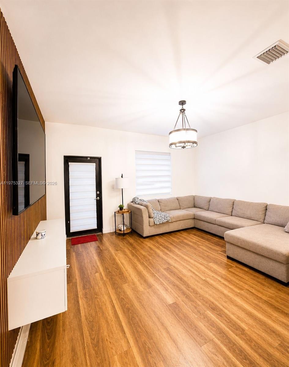 A living room features a large sectional sofa, wood-slat accent wall, and light wood flooring — 24341 SW 118th Path, Homestead FL 33032, HOMESTEAD, FL