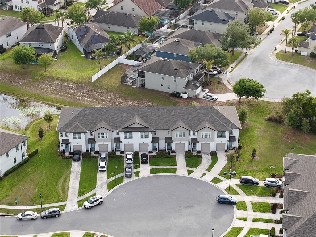 An aerial view shows a multi-unit townhouse building with attached garages and a circular driveway — 1542 DISCOVERY STREET, DAVENPORT, FL