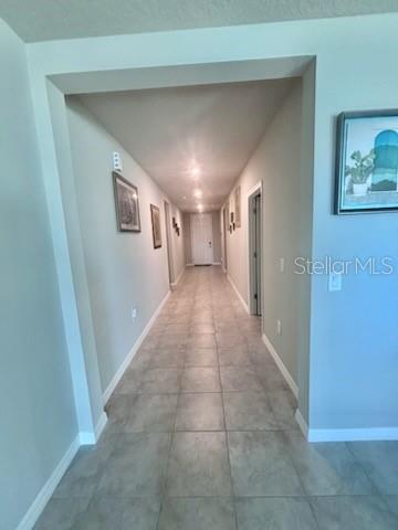 A long hallway with light-colored tile flooring leads to a closed white door — 384 GUADLUPE STREET, HAINES CITY, FL