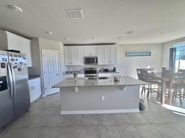 A kitchen features white cabinets, granite countertops, a center island, and stainless steel appliances — 384 GUADLUPE STREET, HAINES CITY, FL