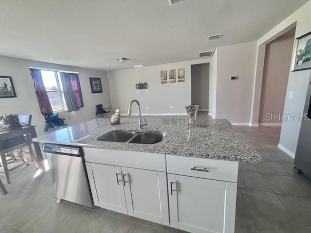 A kitchen island with a granite countertop, stainless steel dishwasher, and white cabinets — 384 GUADLUPE STREET, HAINES CITY, FL