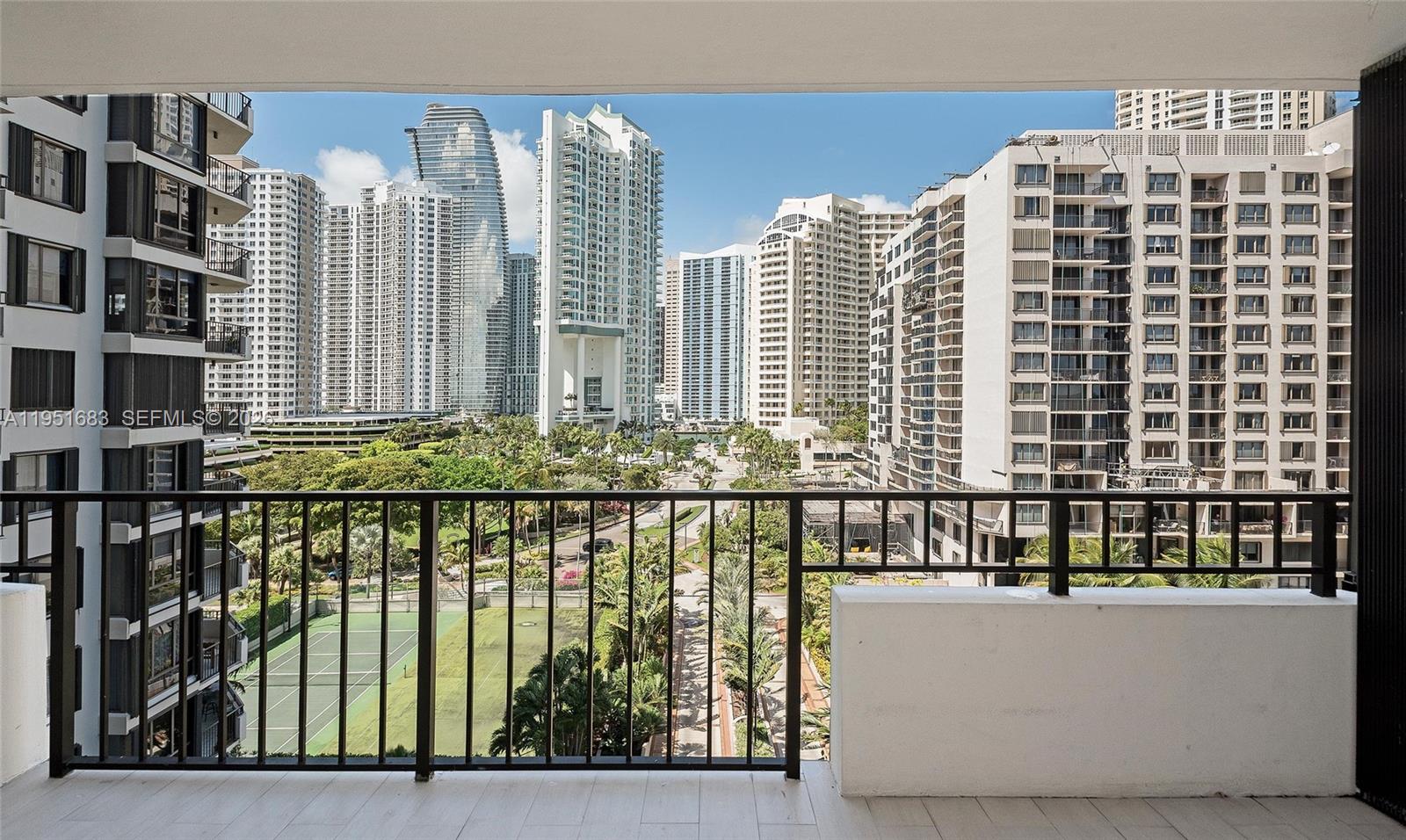 A balcony with a black metal railing overlooks a tennis court and city skyline — 520 Brickell Key Dr # A1010, Miami FL 33131, MIAMI, FL