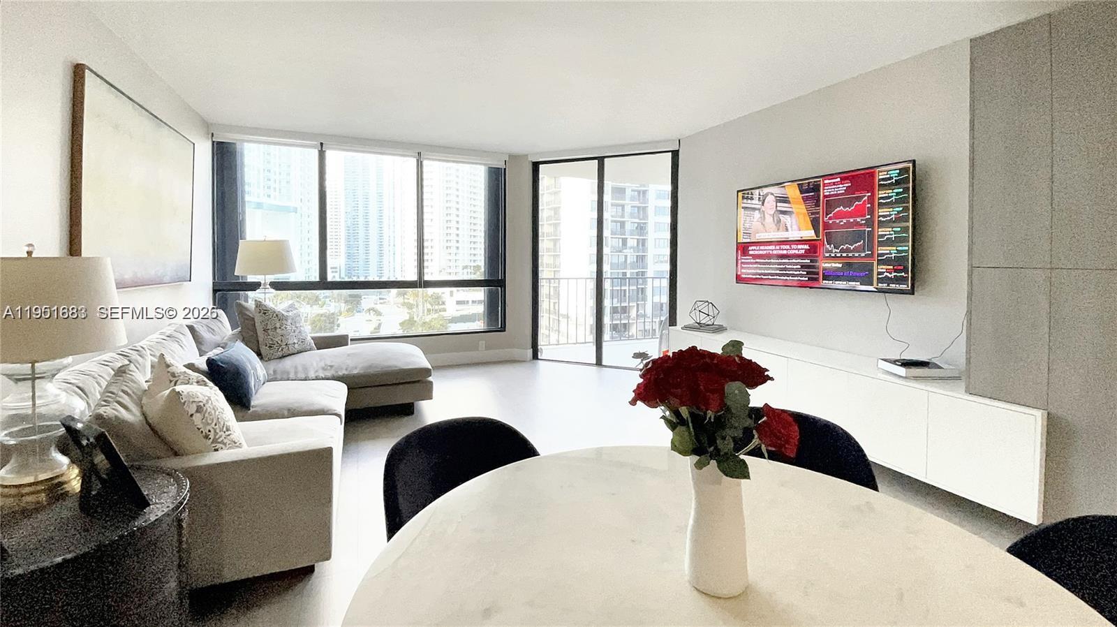 A modern living room features a sectional sofa, a television, and floor-to-ceiling windows — 520 Brickell Key Dr # A1010, Miami FL 33131, MIAMI, FL