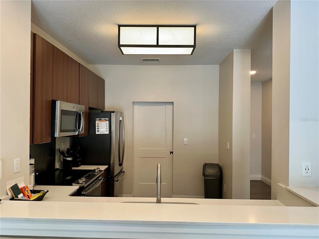 A kitchen features dark wood cabinets, stainless steel appliances, and a white countertop breakfast bar — 14501 GROVE RESORT AVENUE UNIT 2101, WINTER GARDEN, FL