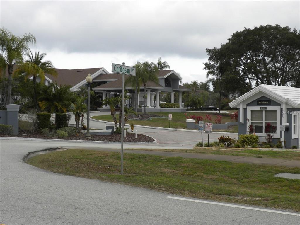 A street sign for Caribbean Drive stands before a gated community entrance with a guardhouse — 251 CARIBBEAN DRIVE, DAVENPORT, FL
