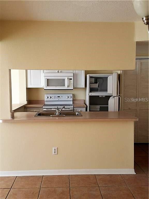 A kitchen with white appliances and cabinets is visible through a pass-through opening — 251 CARIBBEAN DRIVE, DAVENPORT, FL