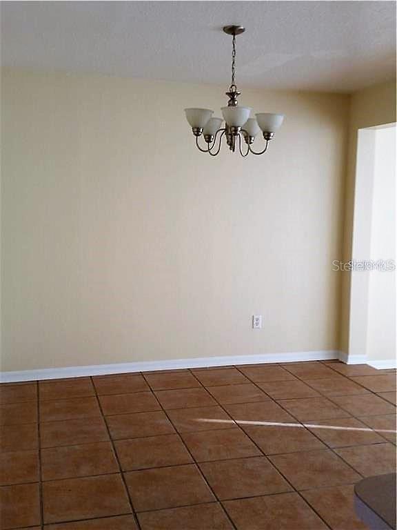 A dining area features tan walls, a five-light chandelier, and brown square floor tiles — 251 CARIBBEAN DRIVE, DAVENPORT, FL