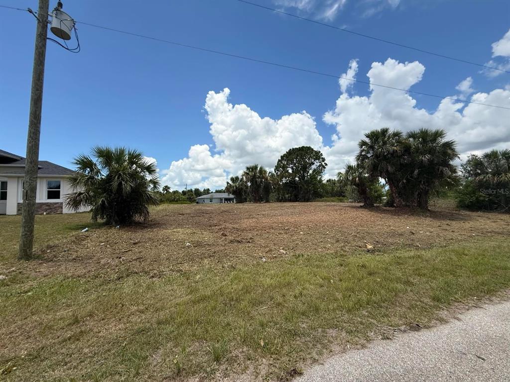 A vacant, cleared residential lot with palm trees under a blue sky with clouds — Lot 22 EASTMAN CIRCLE, NORTH PORT, FL