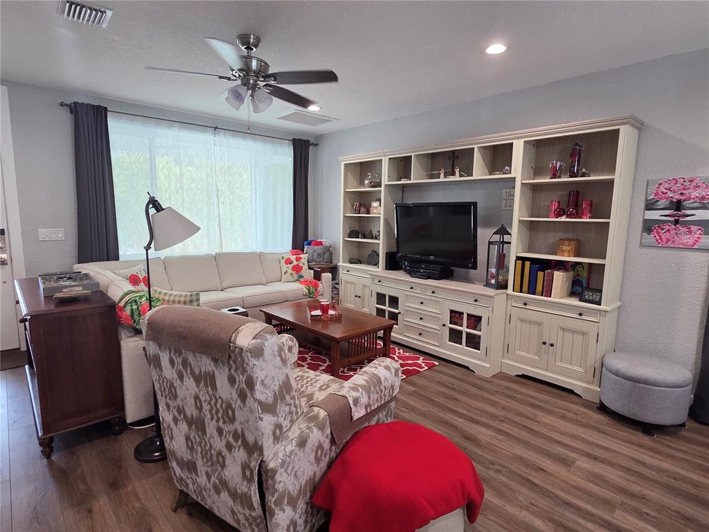 A living room features a large white entertainment center, a sectional sofa, and a patterned armchair — 4325 78TH AVENUE N, PINELLAS PARK, FL