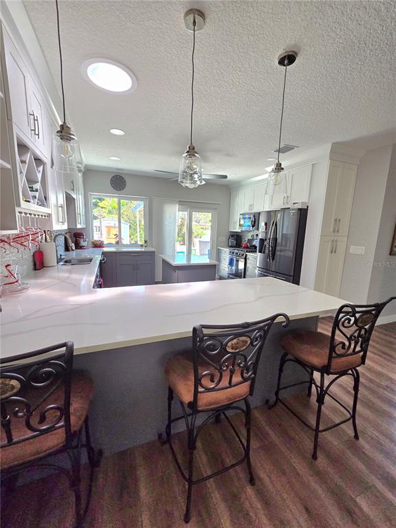 A kitchen features white countertops, dark gray lower cabinets, and three bar stools — 4325 78TH AVENUE N, PINELLAS PARK, FL