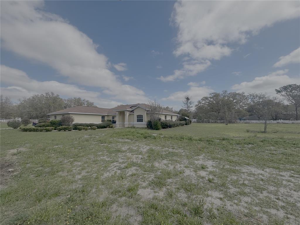 A single-story house with a tan exterior sits on a large, grassy lot — 11435 SW 140TH AVENUE, DUNNELLON, FL