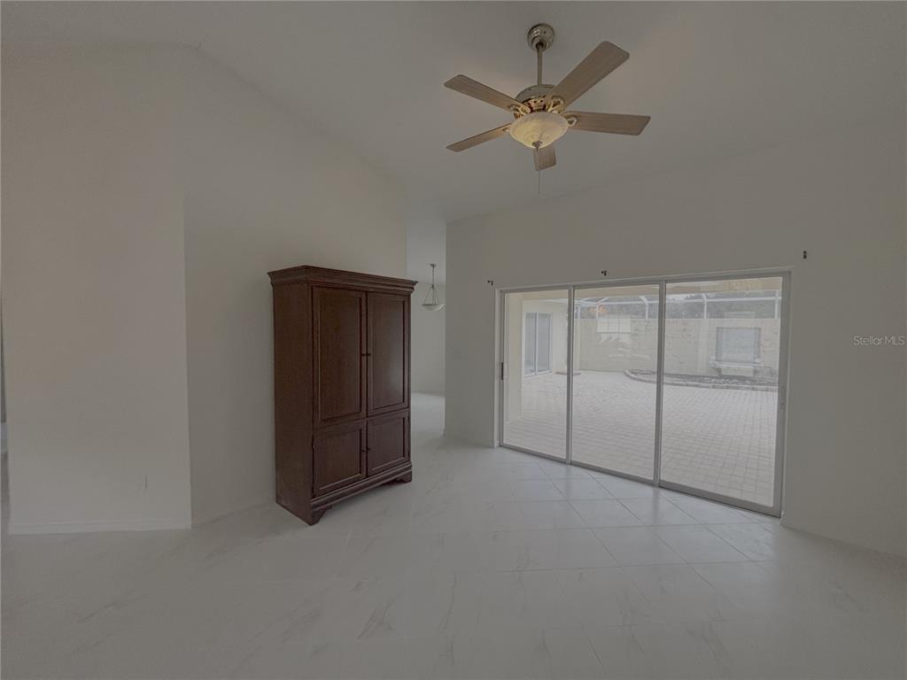 A room with white tile flooring, a dark wood armoire, and sliding glass patio doors — 11435 SW 140TH AVENUE, DUNNELLON, FL