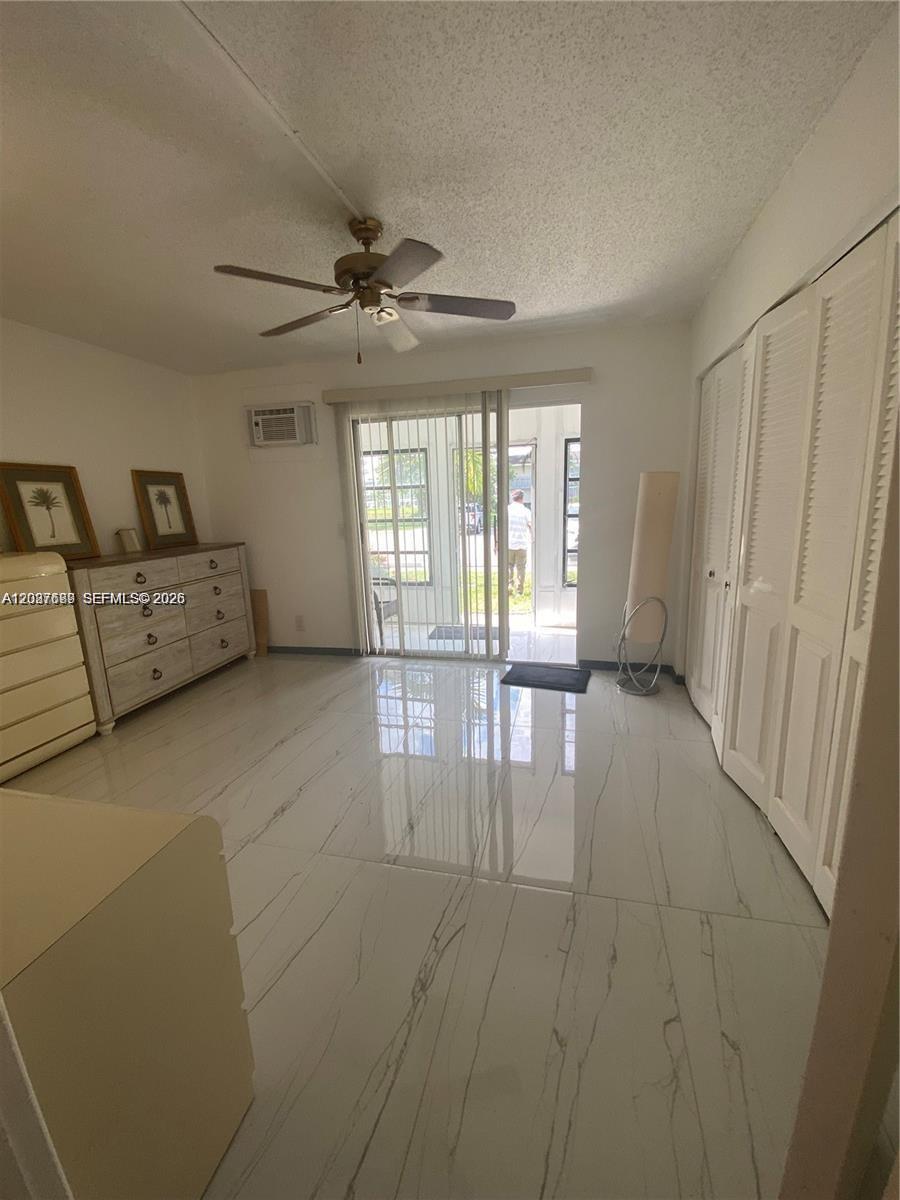 A bedroom with white marble-look tile flooring, a ceiling fan, and sliding glass doors — 111 Tilford F # 111, Deerfield Beach FL 33442, DEERFIELD BEACH, FL